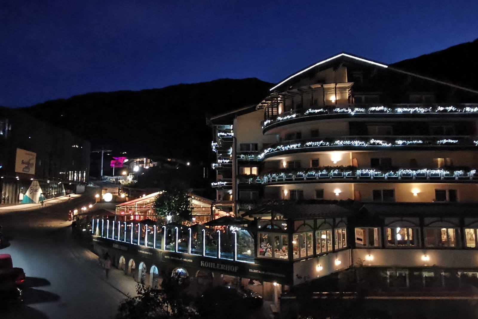 Hotel Kohlerhof in het centrum van Fügen, in de avond, met verlichte balkons.